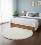 Round white rug on a wooden floor in a bedroom with a bed and nightstands.