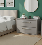 a modern bedroom scene that prominently features a grey, two-drawer nightstand. This piece of furniture is identified as a Hudson Reed Lille 600mm Floor Standing 2-Drawer Vanity unit, potentially in a "Coastal Grey" or "Pebble Grey" finish. 