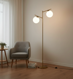Modern floor lamp with two round lights in a room with a chair and small table.
