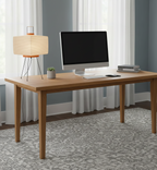 Wooden desk with computer setup in a room with curtains and rug
