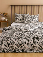 Bed with black and white leaf pattern bedding in a bedroom setting.