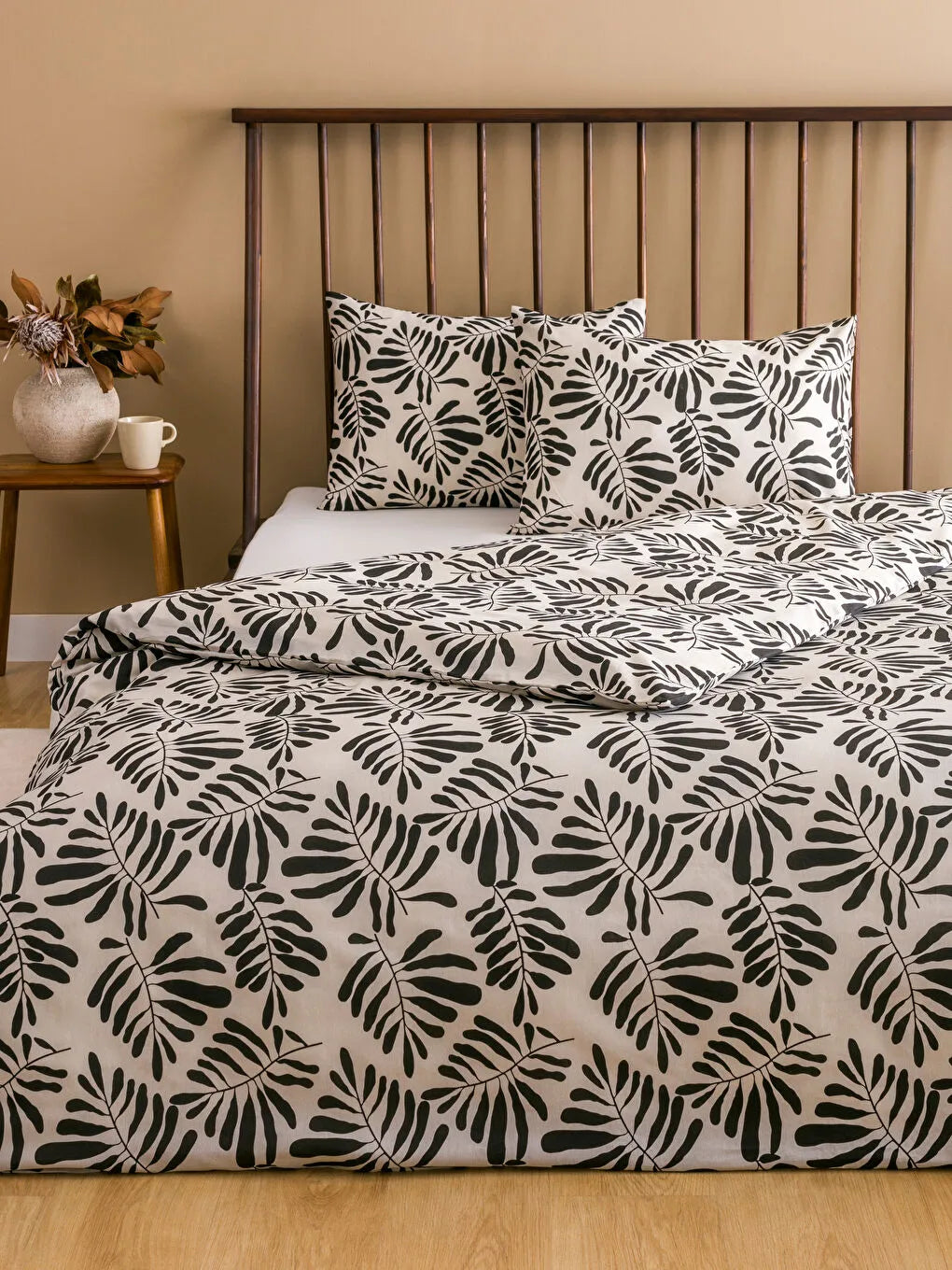 Bed with black and white leaf pattern bedding in a bedroom setting.